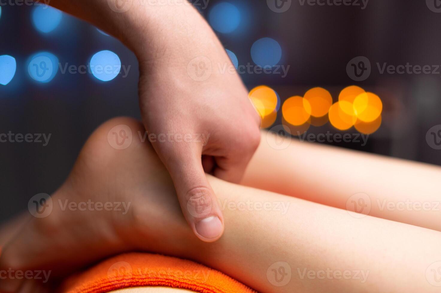 fermer dans peu profond profondeur de champ de une Masculin masseur mains masser le Achille tendon de une femelle jambe. professionnel massage dans une professionnel pièce photo