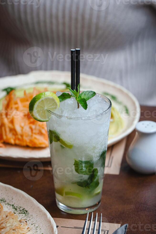 du froid Mojito verre avec citron, menthe, et une sorbet avec nourriture dans le Contexte photo