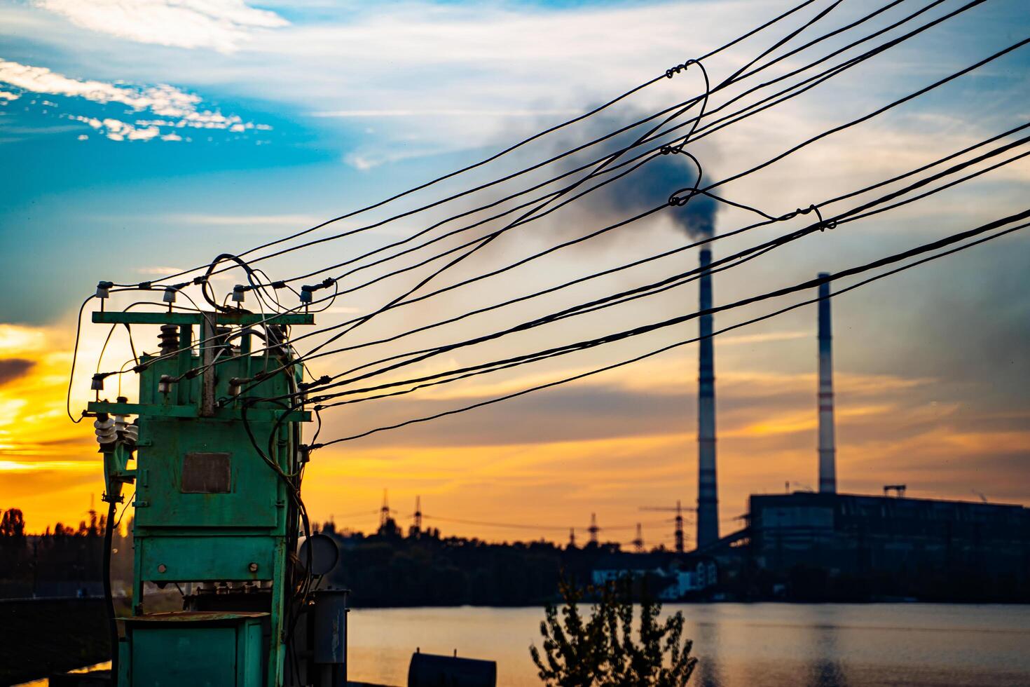 une vue de une Puissance plante et une corps de l'eau à le coucher du soleil photo