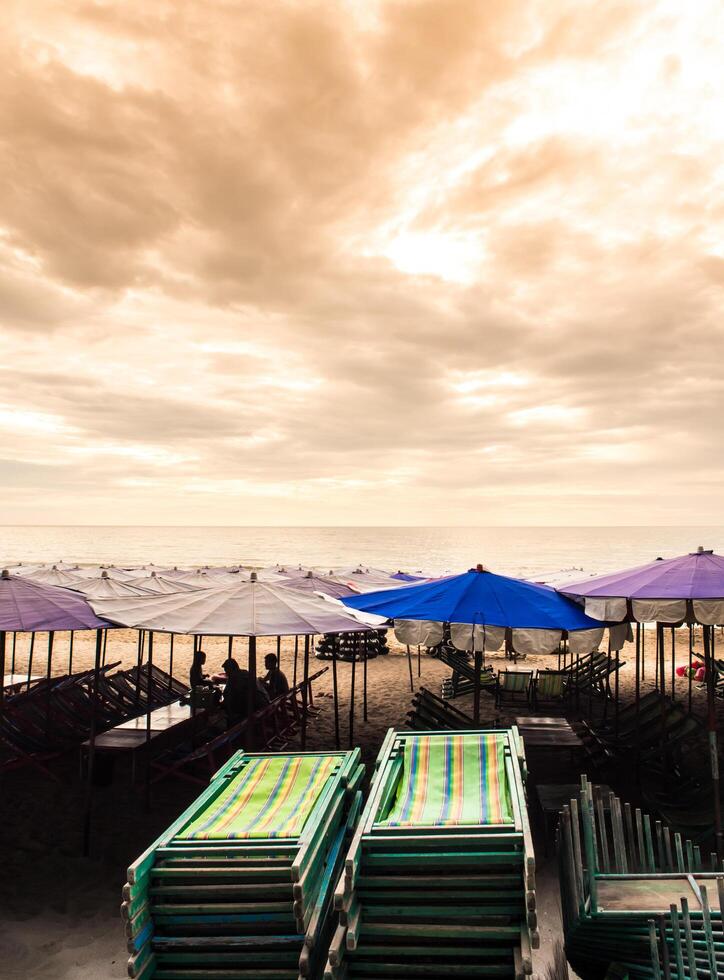 coloré Toile lit de repos en dessous de le plage parapluie photo