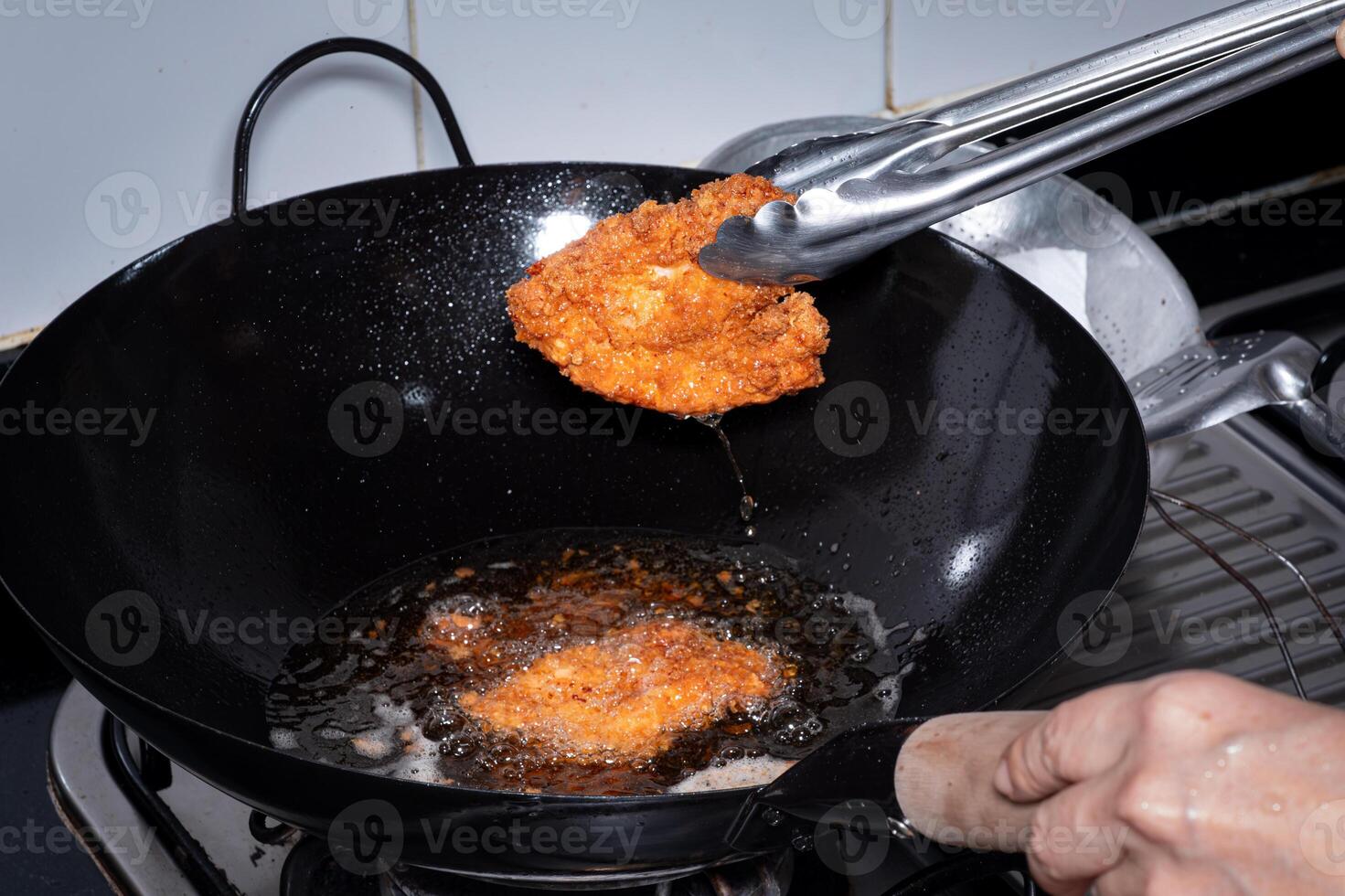 pané frit poulet. nourriture frit dans ébullition pétrole dans une chinois wok. cuisine par friture dans chaud huile. bulles apparaître de friture photo