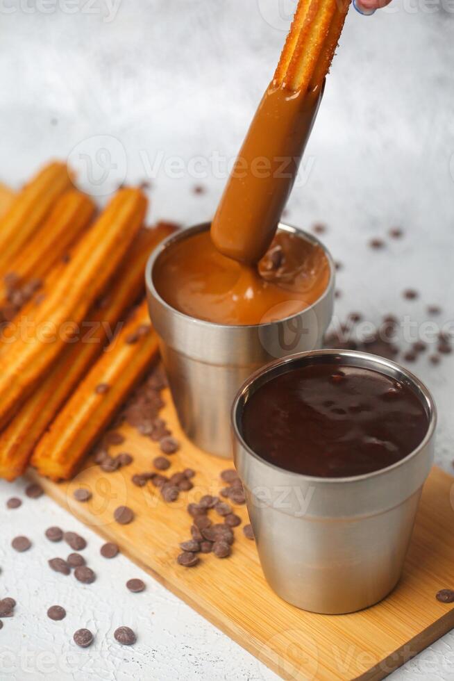 la personne plongement Churros dans une tasse de Chocolat photo