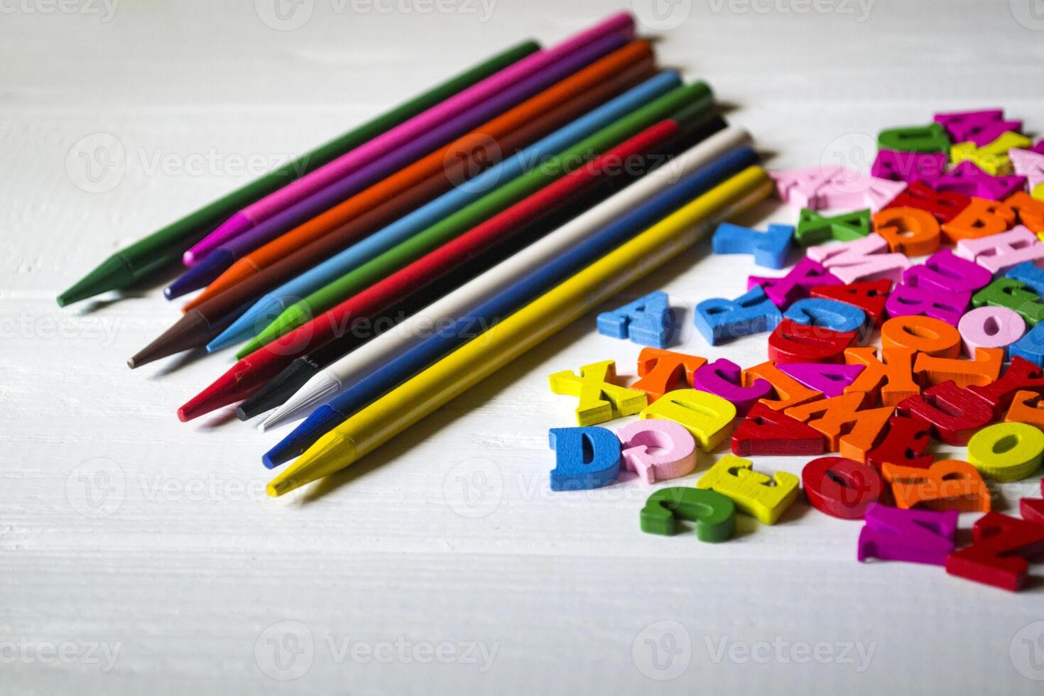 multicolore des lettres et ensemble de des crayons sur le tableau. coloré en bois alphabet et des crayons sur une tableau. photo