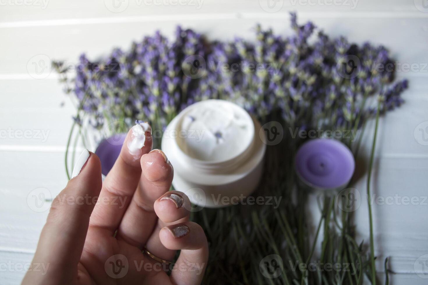 lavande fleurs, bougies, crème et femelle main sur une blanc en bois Contexte. beauté se soucier. Haut voir. photo