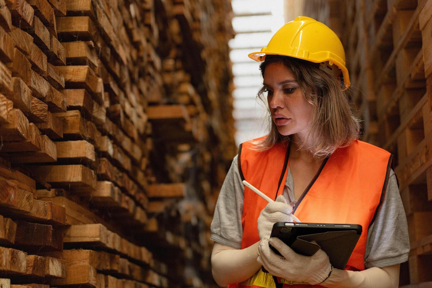 femme ouvrier Charpentier portant sécurité uniforme et difficile chapeau travail et vérification le qualité de en bois des produits à atelier fabrication. homme et femme ouvriers bois dans foncé entrepôt industrie. photo