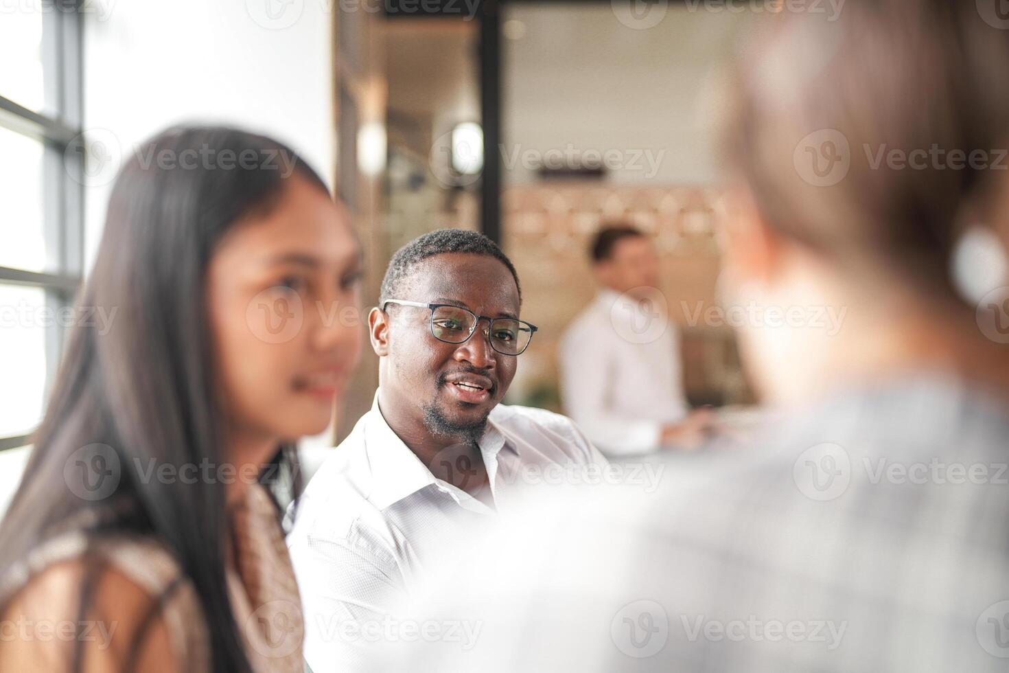 concentrer de intelligent africain homme d'affaire. diverse des employés recueillies dans Bureau ayant amusement réflexion tandis que discuter Nouveau des idées projet. multiracial collègues de travail réunion à cotravail espace zone. photo