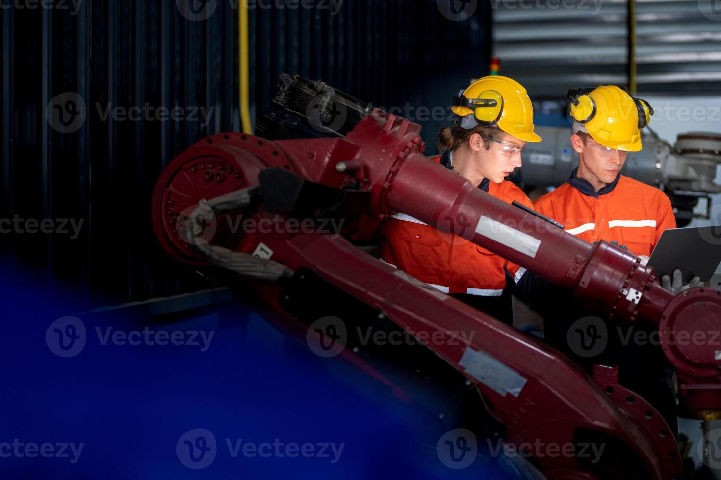 groupe de Masculin ingénieur ouvriers entretien automatique robotique bras machine dans une foncé pièce usine. ouvrier vérification et réparer automatique robot main machine. ouvrier portant sécurité des lunettes et casque. photo