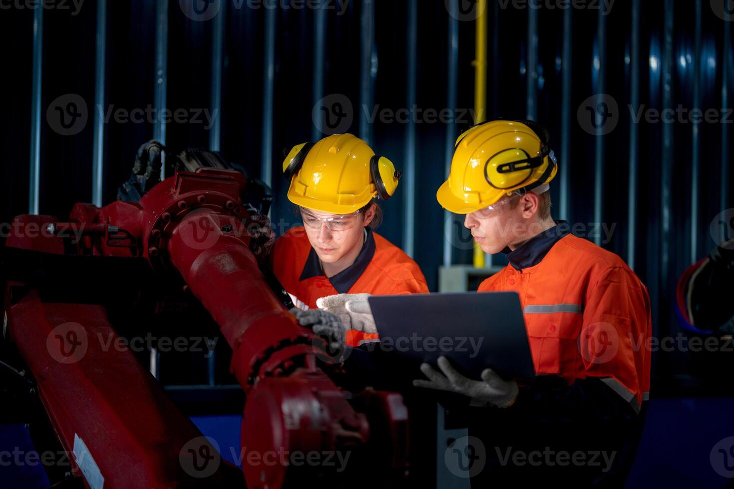 groupe de Masculin ingénieur ouvriers entretien automatique robotique bras machine dans une foncé pièce usine. ouvrier vérification et réparer automatique robot main machine. ouvrier portant sécurité des lunettes et casque. photo