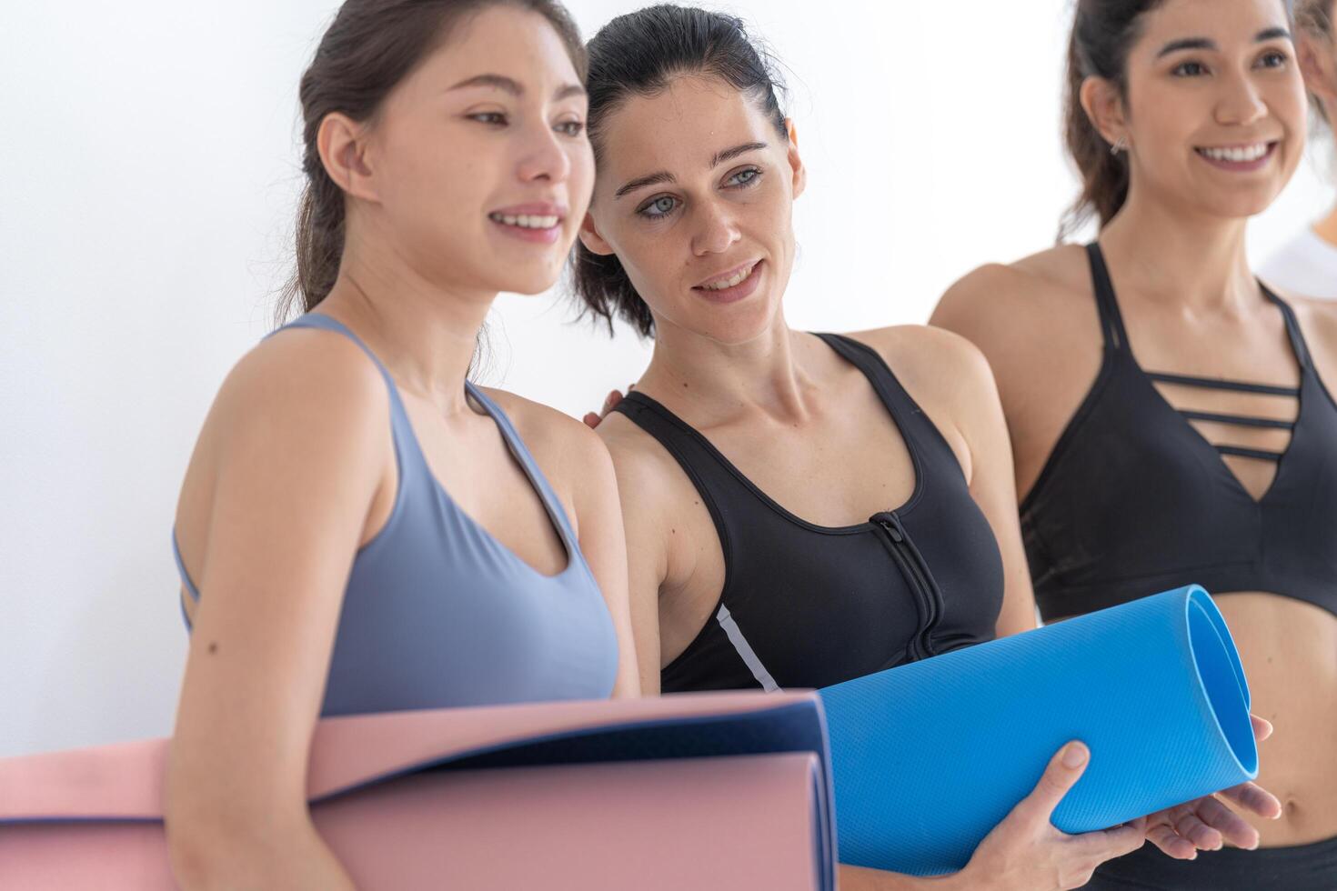 groupe de content sportif femmes et gars portant corps élégant tenue de sport en portant personnel les tapis penché sur une blanc Contexte. attendre pour yoga classe ou corps poids classe. en bonne santé mode de vie et bien-être photo