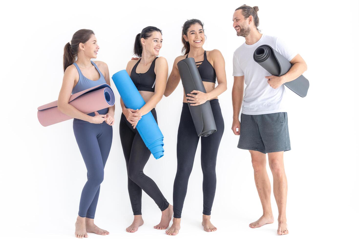 groupe de content sportif femmes et gars portant corps élégant tenue de sport en portant personnel les tapis penché sur une blanc Contexte. attendre pour yoga classe ou corps poids classe. en bonne santé mode de vie et bien-être photo