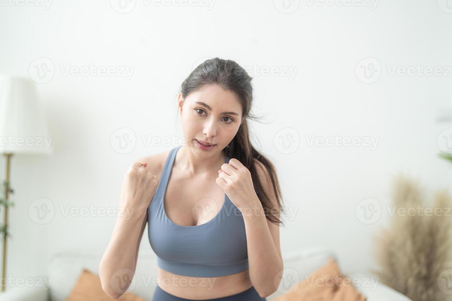 attrayant et fort femme élongation avant aptitude à intérieur maison. en bonne santé mode de vie. femme chaud en haut par boxe dans le air. Jeune femelle avec svelte corps perforation boxe jeu de jambes cardio exercer. photo