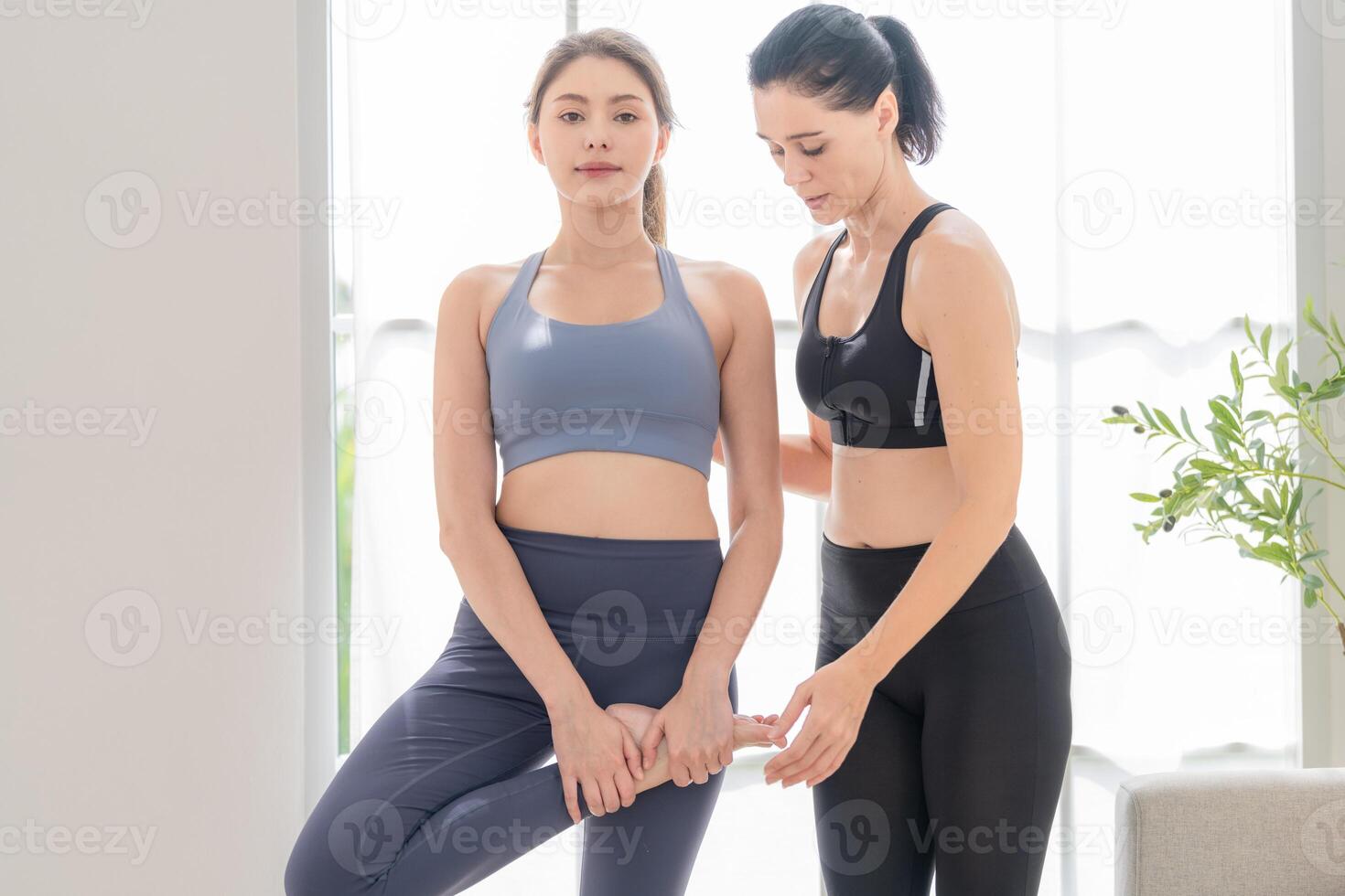 deux femmes sur de soi formation yoga. athlétique femmes dans tenue de sport Faire aptitude élongation des exercices à Accueil dans le vivant chambre. sport et des loisirs concept. yoga prof est portion Jeune femme. photo