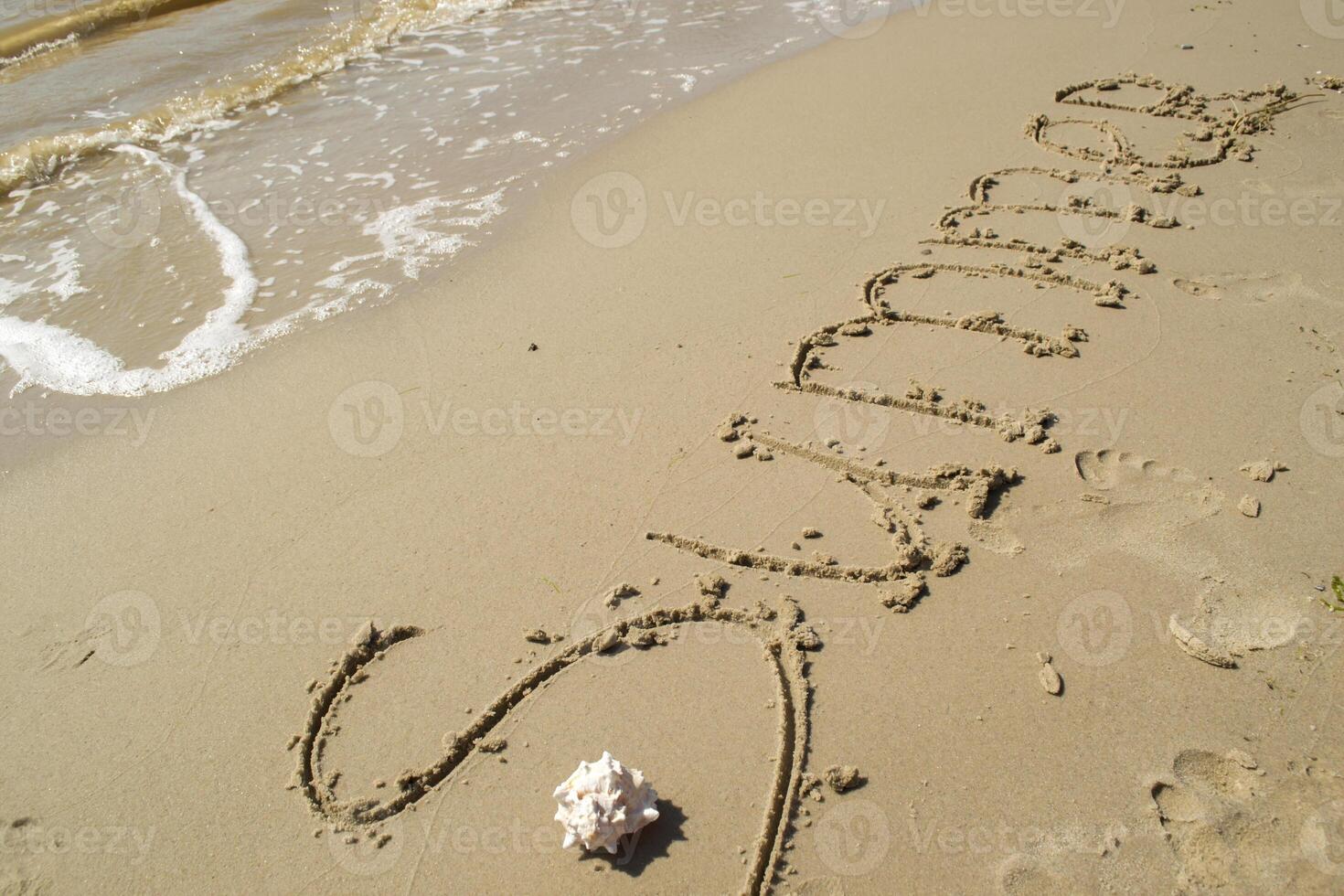 le mot été est écrit sur le le sable par main. photo