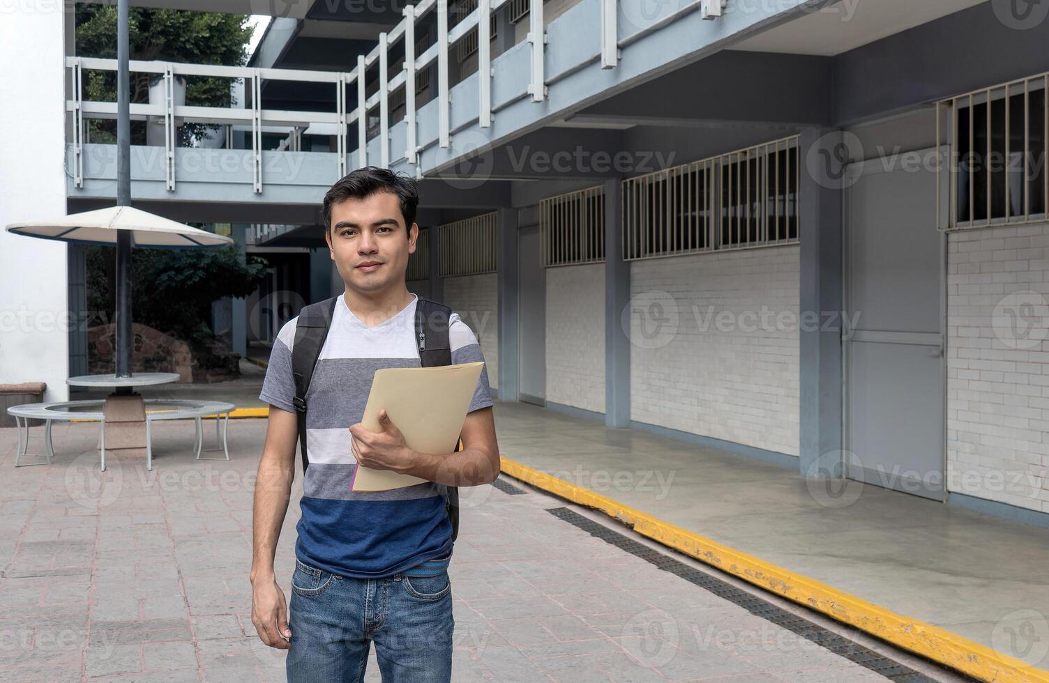 une Masculin étudiant à le Université en portant une papier dans le sien main photo