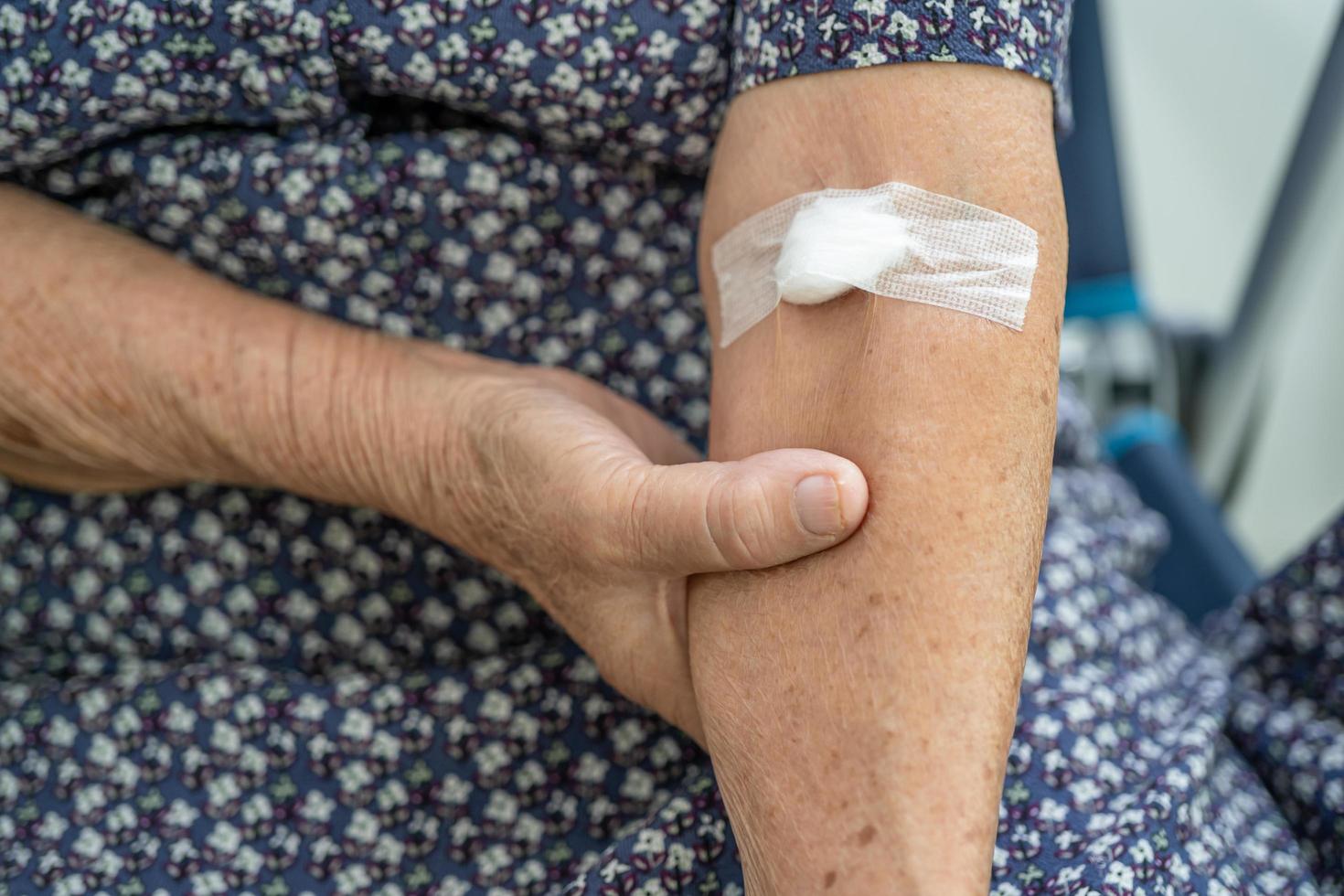 Une patiente asiatique âgée ou âgée montre que le coton arrête de saigner, après des tests sanguins pour un bilan de santé physique annuel afin de vérifier le cholestérol, la pression artérielle et le taux de sucre. photo