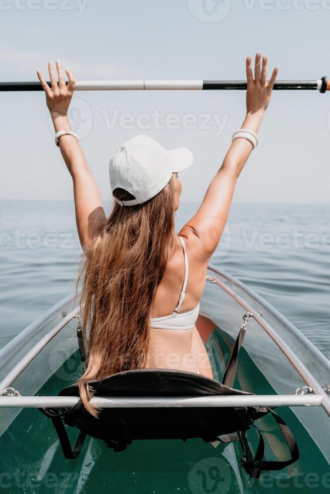 femme dans kayak retour voir. content Jeune femme avec longue cheveux flottant dans transparent kayak sur le cristal clair mer. été vacances vacances et de bonne humeur femelle gens relaxant ayant amusement sur le bateau photo