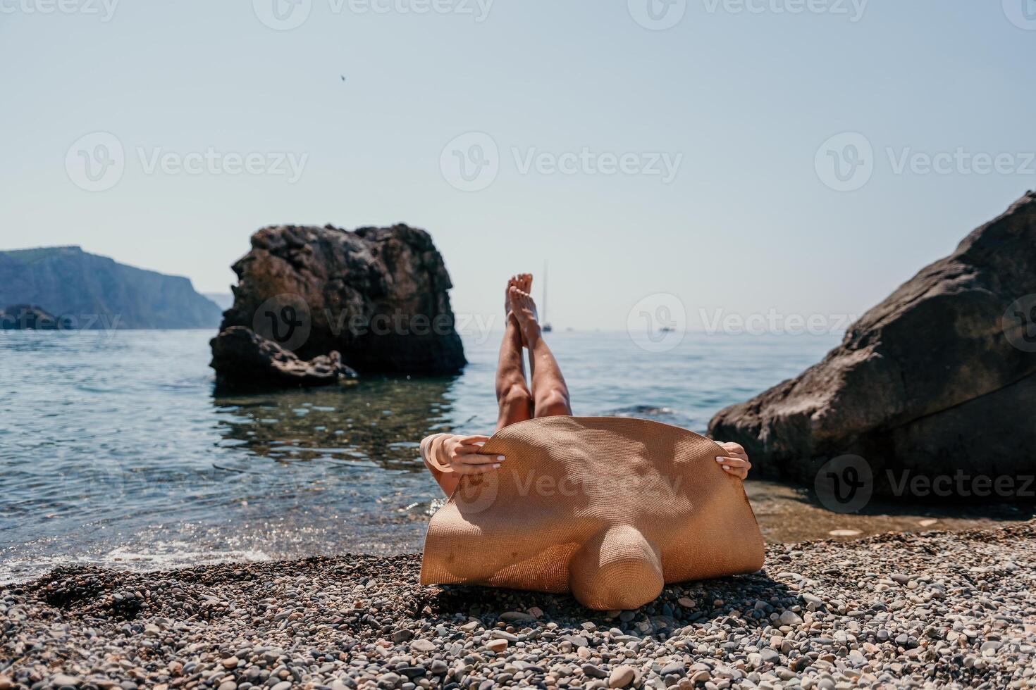 femme Voyage mer. content touristique dans chapeau prendre plaisir prise image en plein air pour souvenirs. femme voyageur posant sur le plage à mer entouré par volcanique montagnes, partage Voyage aventure périple photo