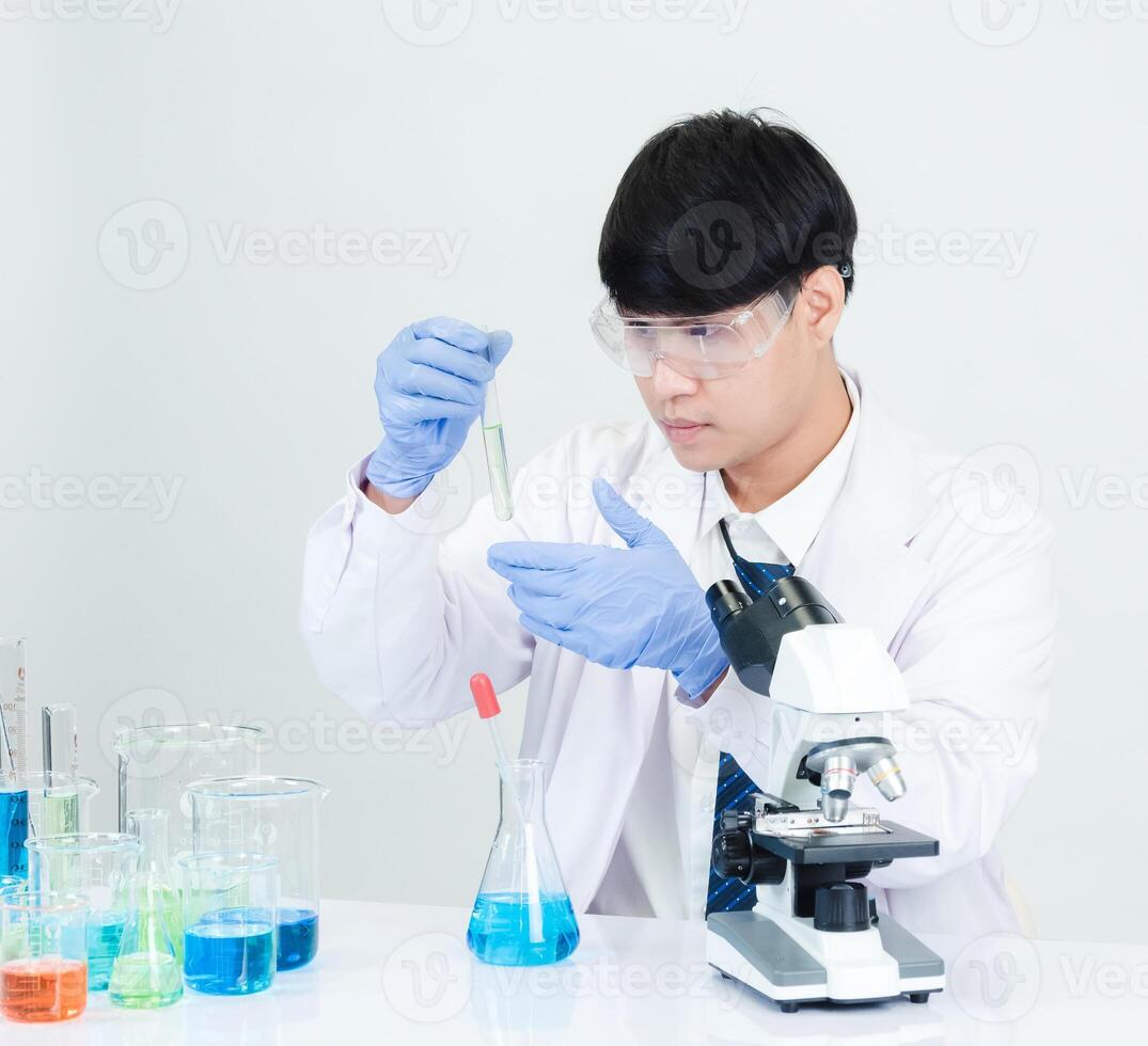 portrait asiatique homme étudiant scientifique médecin robe un la personne sti dans laboratoire à la recherche main en portant tester tube chimiste. causé par mélange réactifs dans scientifique recherche laboratoires et microscope sur table photo