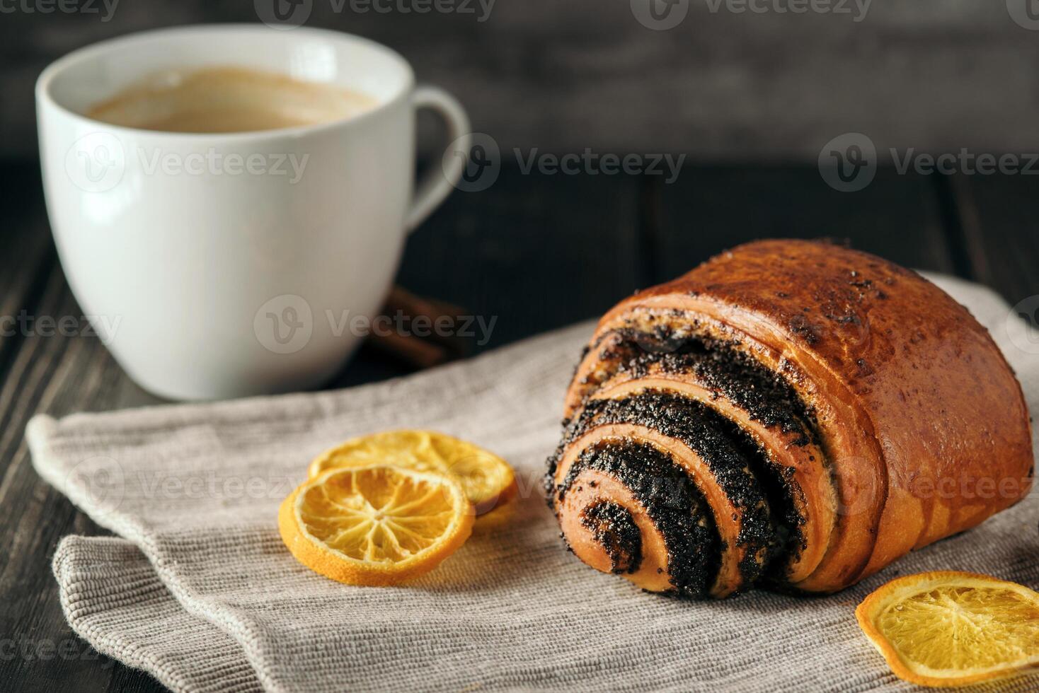 petits pains avec coquelicot des graines et une tasse de café sur foncé bois Contexte avec serviette de table photo