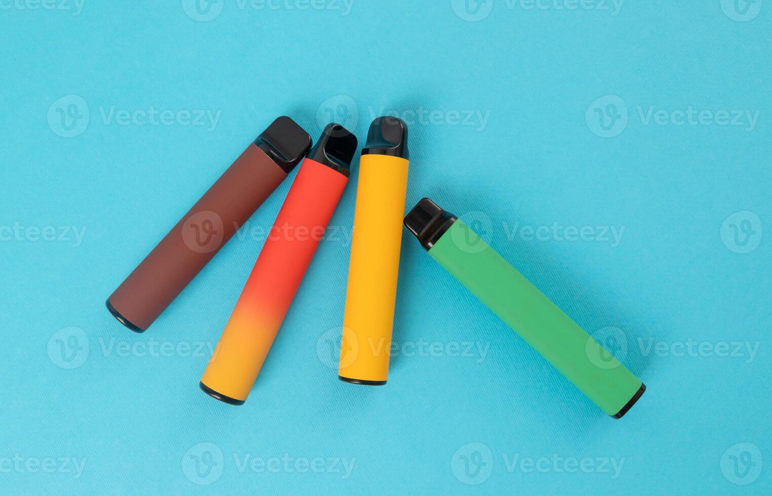 ensemble de coloré jetable électronique cigarettes sur une bleu Contexte. le concept de moderne fumeur. Haut vue photo