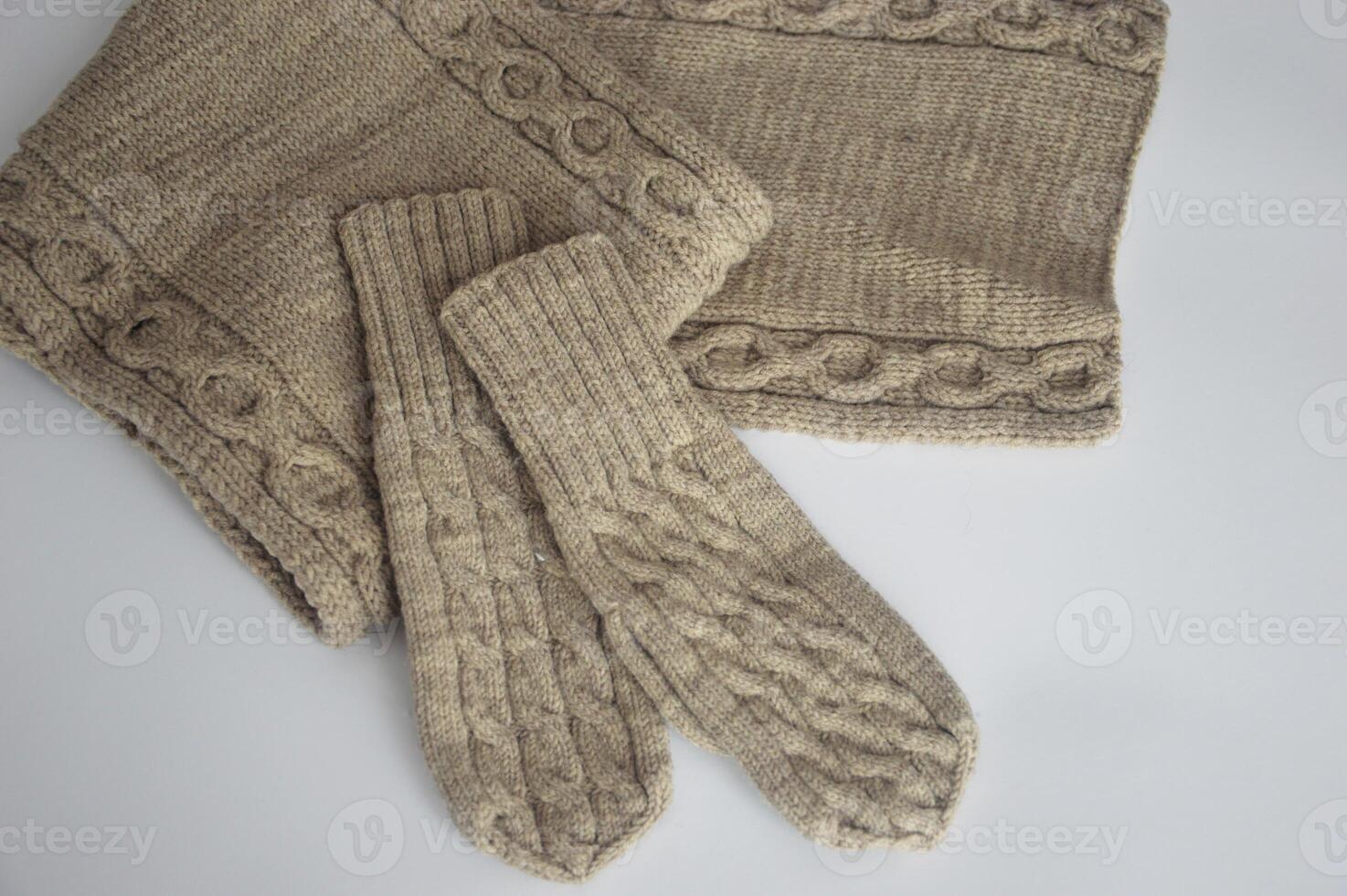 beige tricoté la laine Mitaines avec une texturé modèle et une écharpe sur une blanc Contexte. hiver accessoires. photo