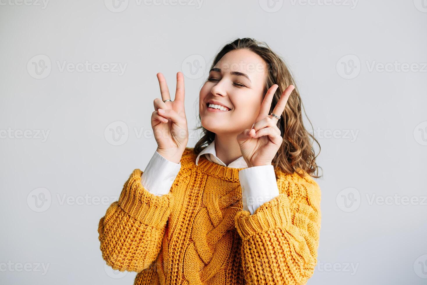 Jeune femme modèle pose avec joyeux gestes - joyeux, espiègle, et jolie - souriant et en riant avec la victoire et paix panneaux - positif et mignonne expression - joyeux isolement sur blanc Contexte. photo