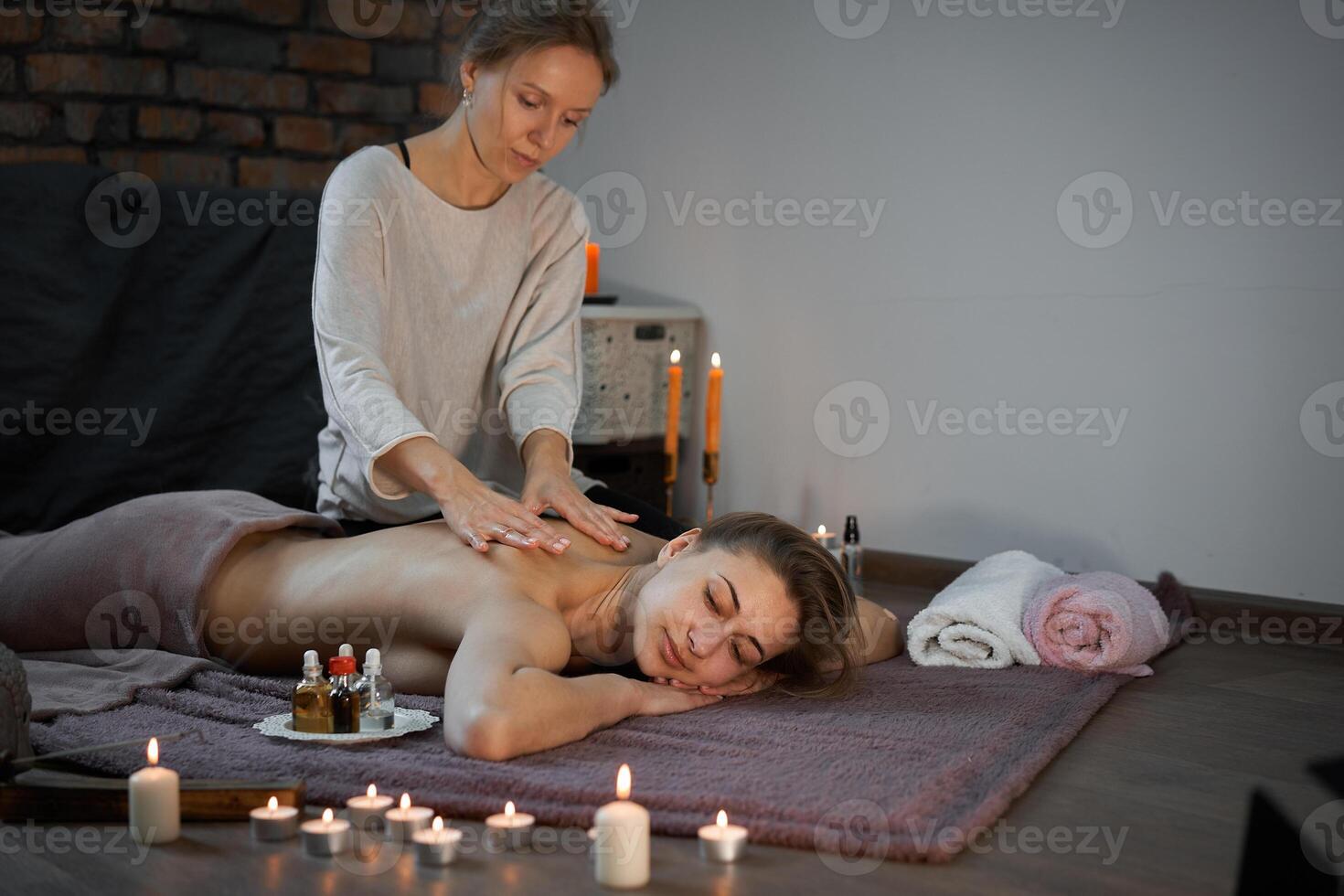 se détendre et prendre plaisir dans spa salon, avoir massage par professionnel masseur. femme mensonge avec nu retour se détendre sur sol couverture photo