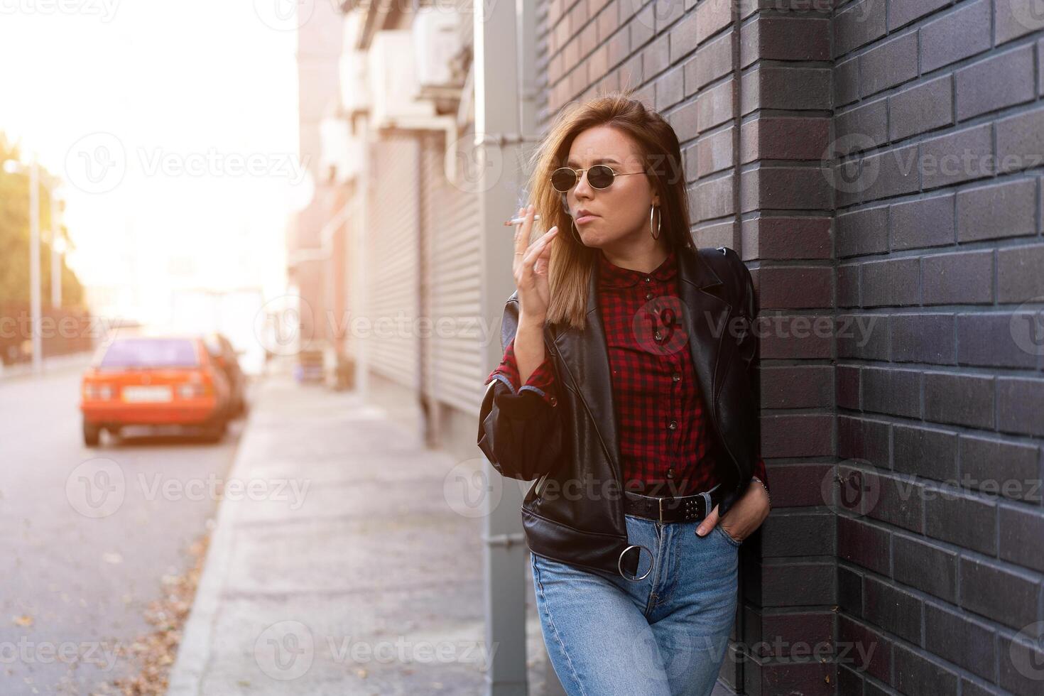 magnifique Jeune avec style habillé caucasien fille fume cigarette sur le rue. photo