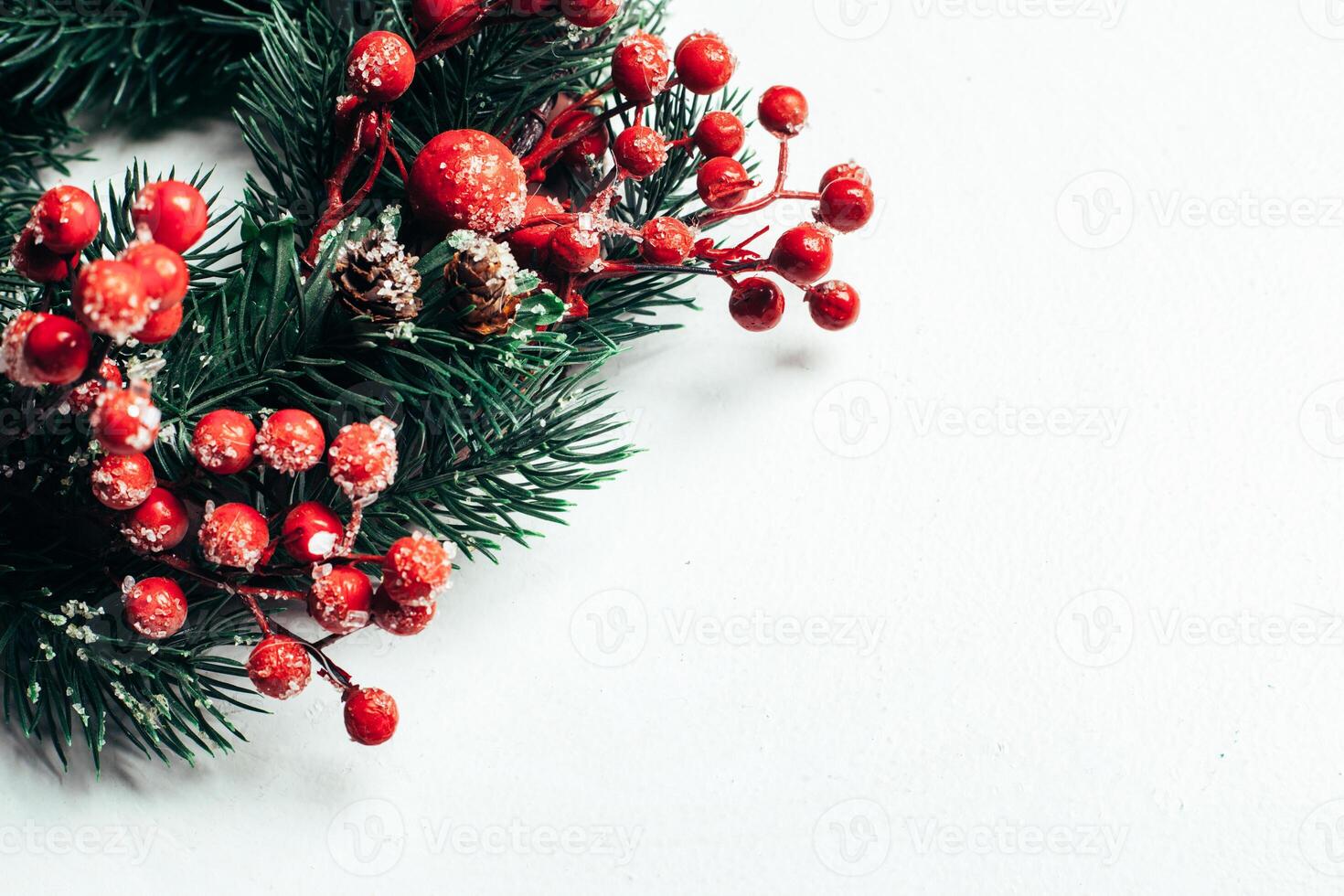 Noël décoratif couronne de houx, lierre, du gui, cèdre et leyland feuille brins avec rouge baies plus de blanc Contexte. photo