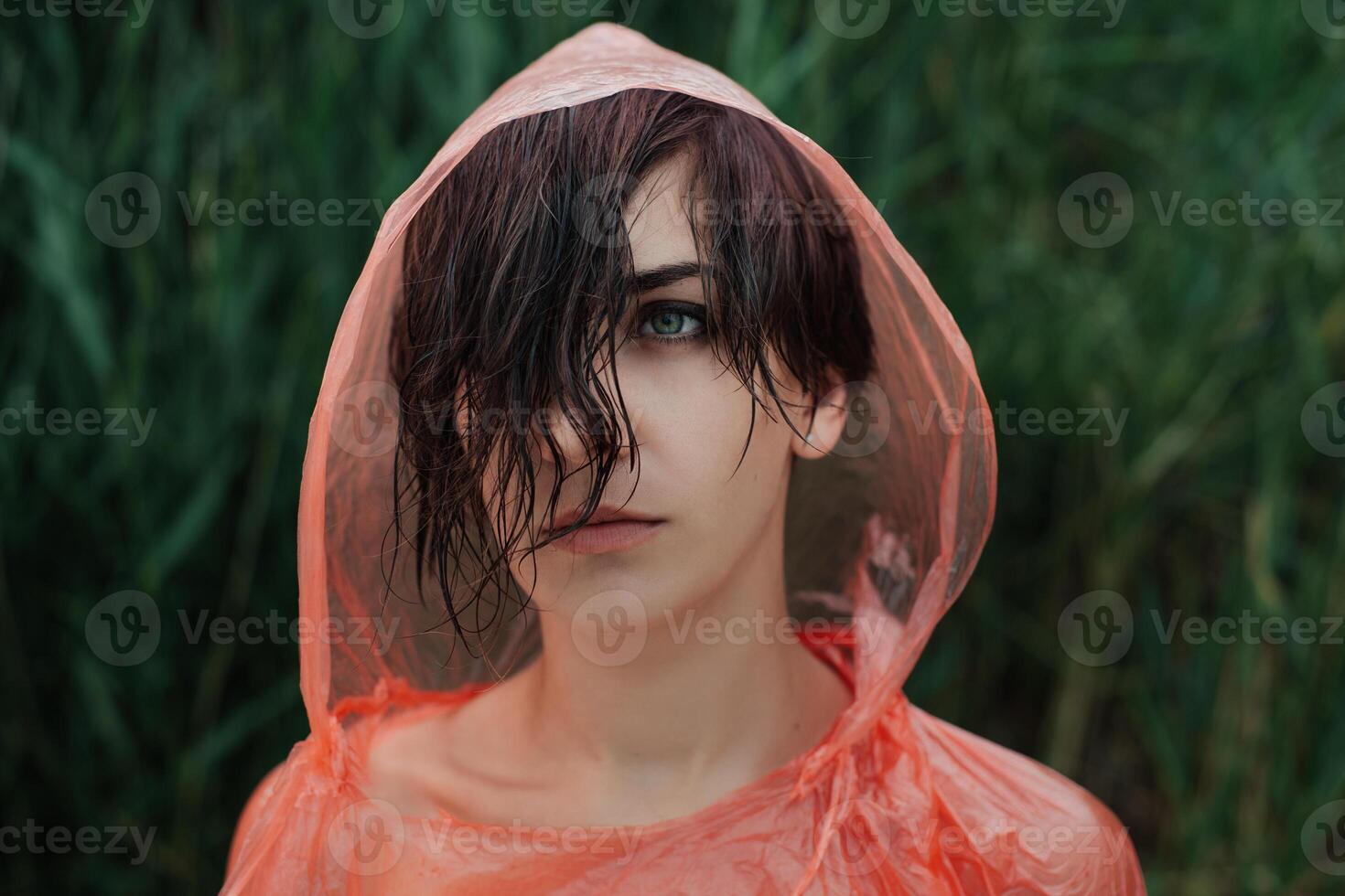 le portrait de fille dans rouge imperméable en dessous de le pluie. photo