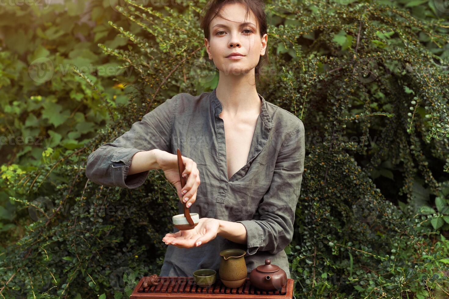 Oriental Maître de thé la cérémonie dans été parc. traditionnel thé fête sur le la nature avec femme habillé dans le gris chemise photo