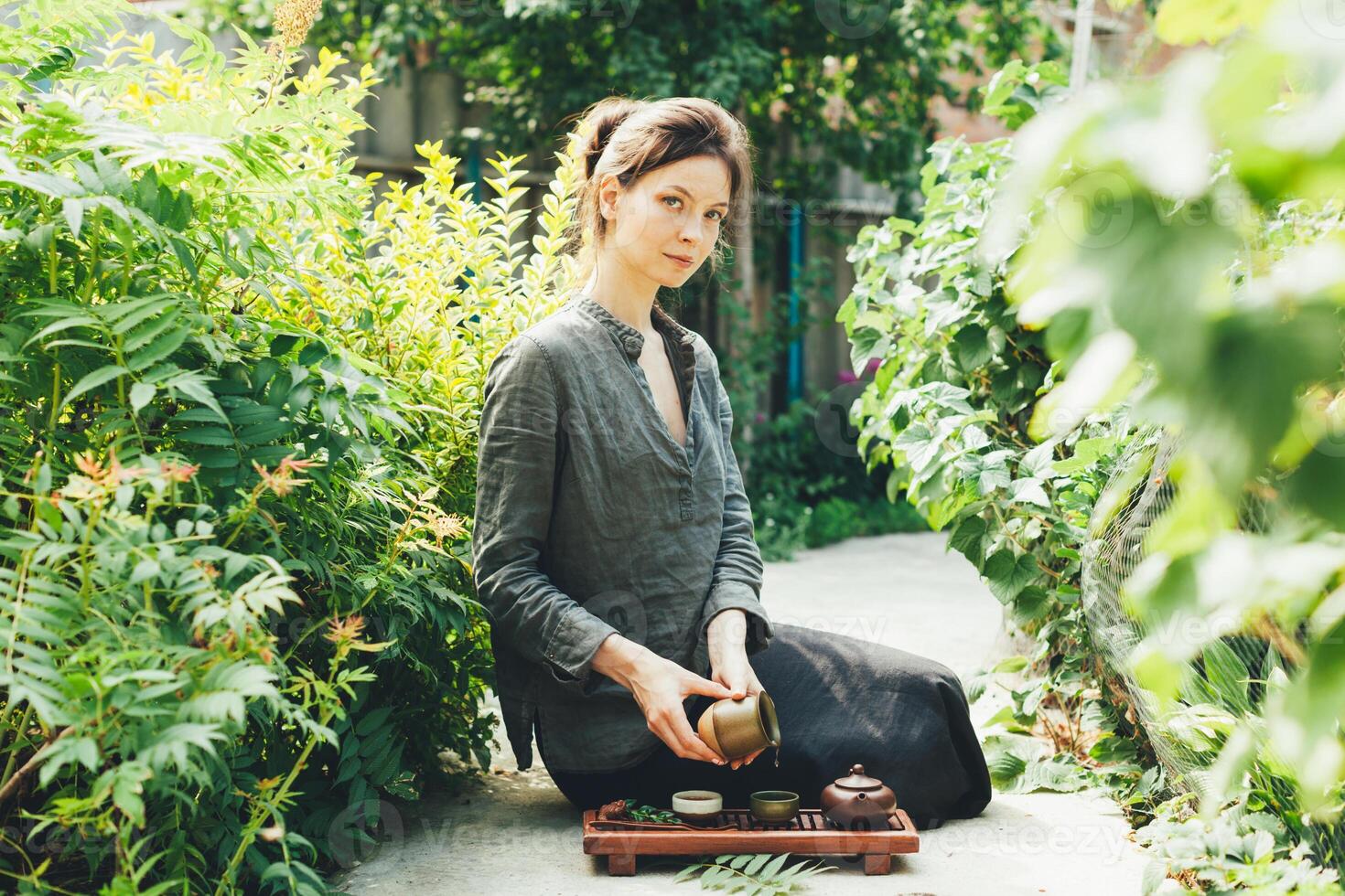 Oriental Maître de thé la cérémonie dans été parc. traditionnel thé fête sur le la nature avec femme habillé dans le gris chemise photo