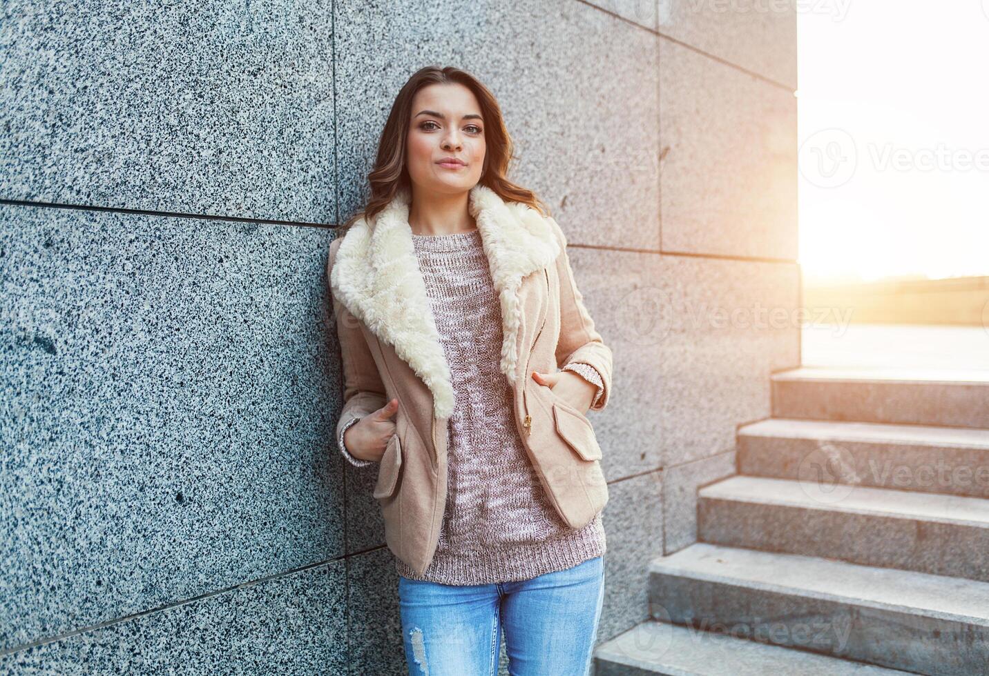 une magnifique Jeune brunette fille des promenades par le l'automne ville dans le des rayons de chaud lumière du soleil photo