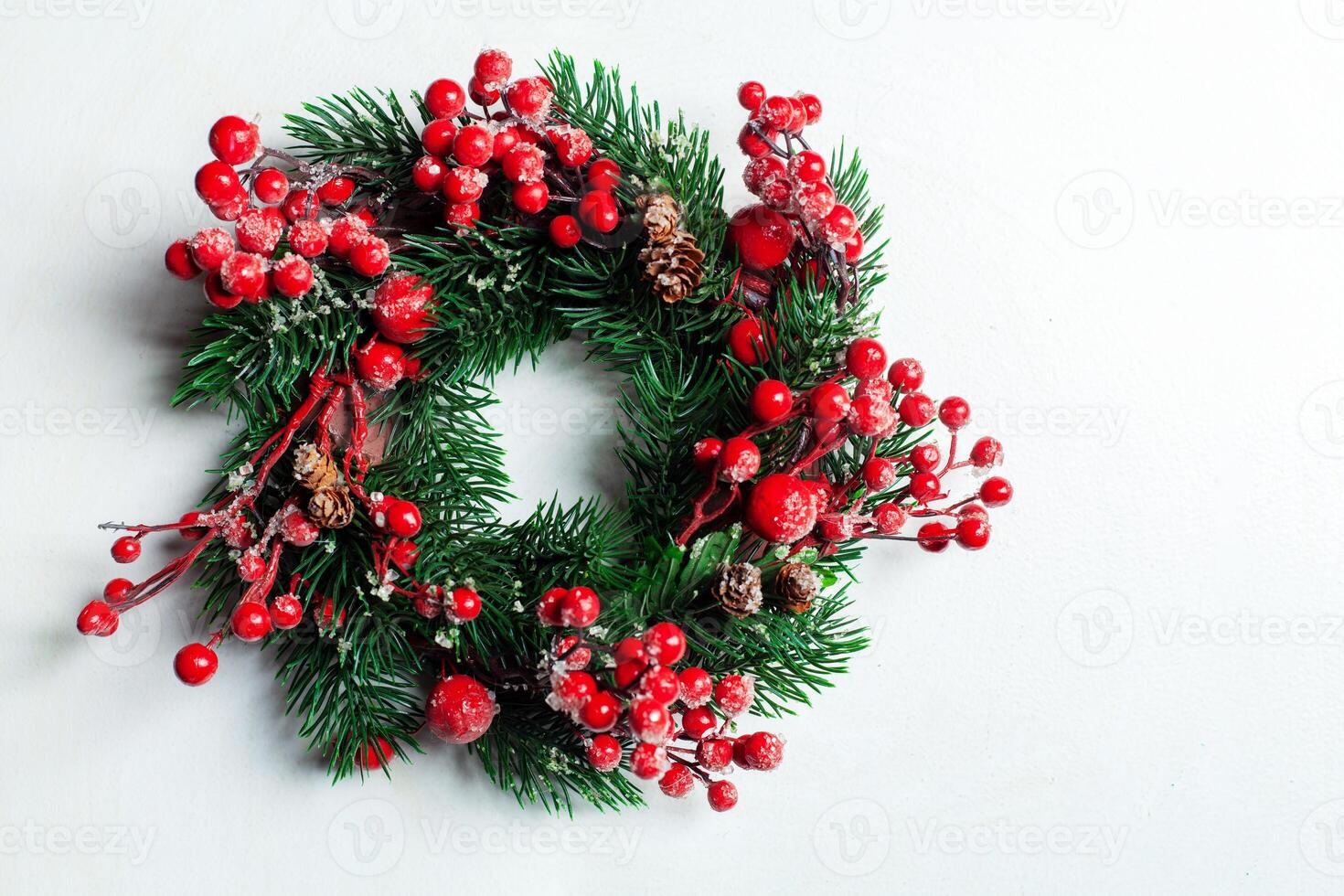 Noël décoratif couronne de houx, lierre, du gui, cèdre et leyland feuille brins avec rouge baies plus de blanc Contexte. photo