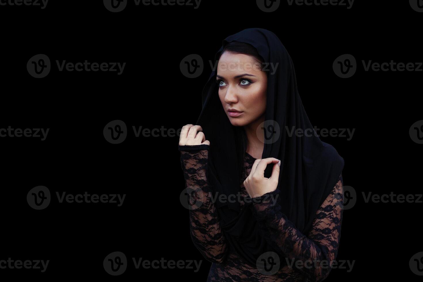 Jeune magnifique femme avec une noir cheveux dans le noir capuche et chemisier à le noir Contexte photo