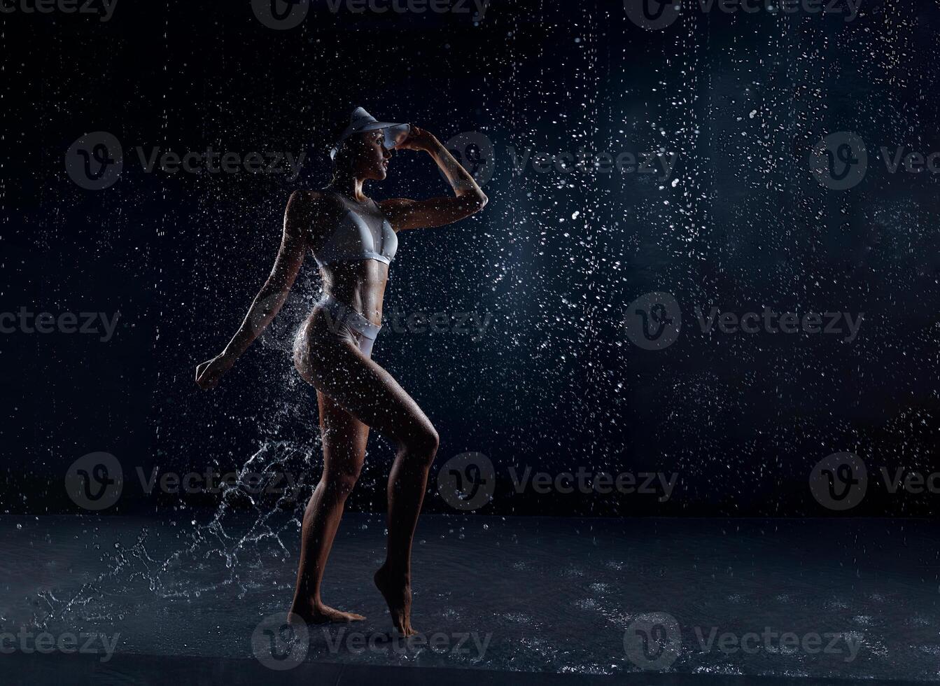 magnifique athlétique caucasien fille avec une parfait figure est permanent en dessous de le l'eau. aptitude femme dans une vaporisateur de l'eau. des sports fraîcheur. concept photo