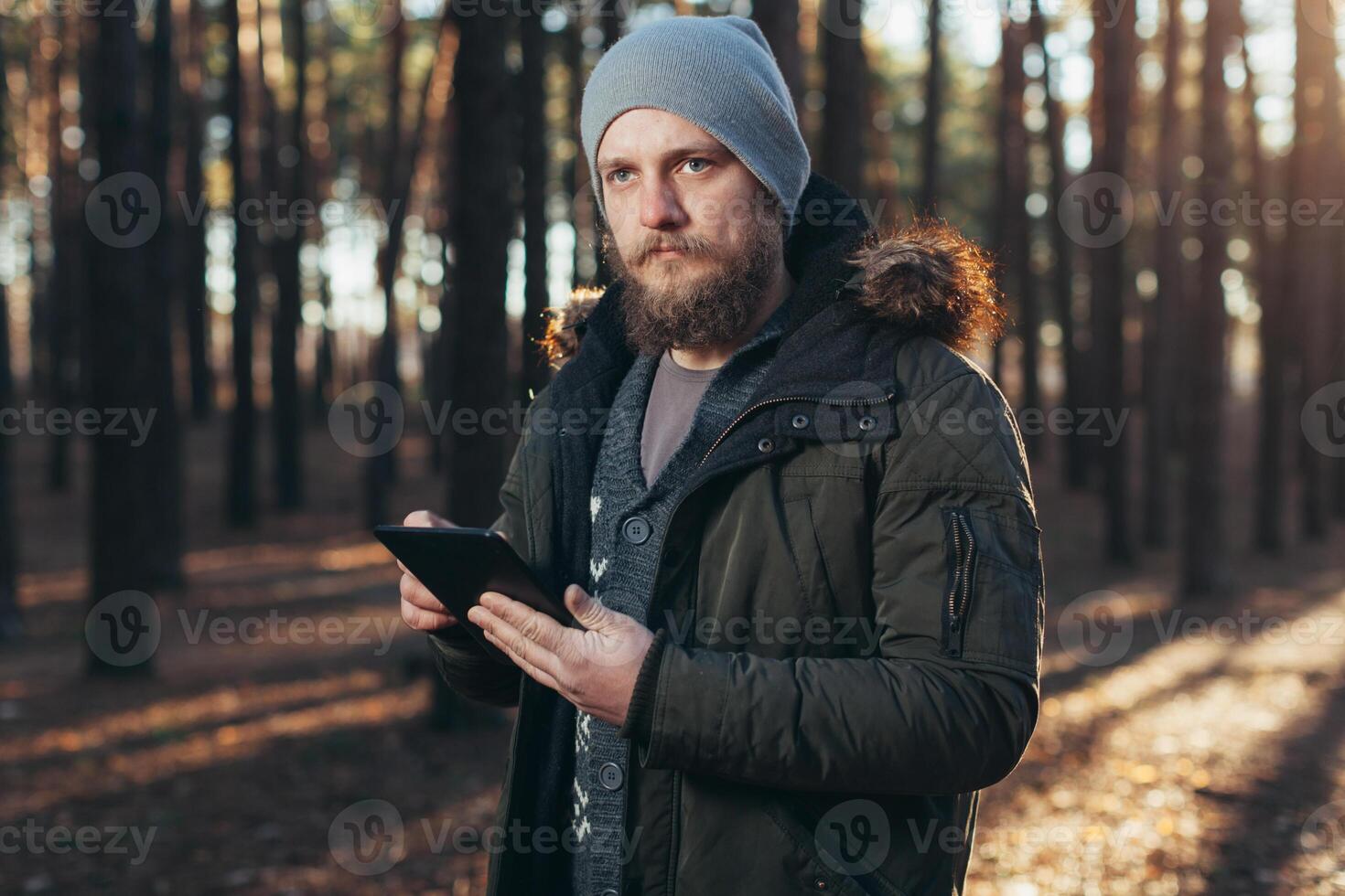 proche en haut portrait de adulte Masculin promeneur en utilisant numérique languette et à la recherche pour emplacement pendant une randonnée dans la nature. homme sur une randonnée en utilisant numérique tablette pour la navigation. photo