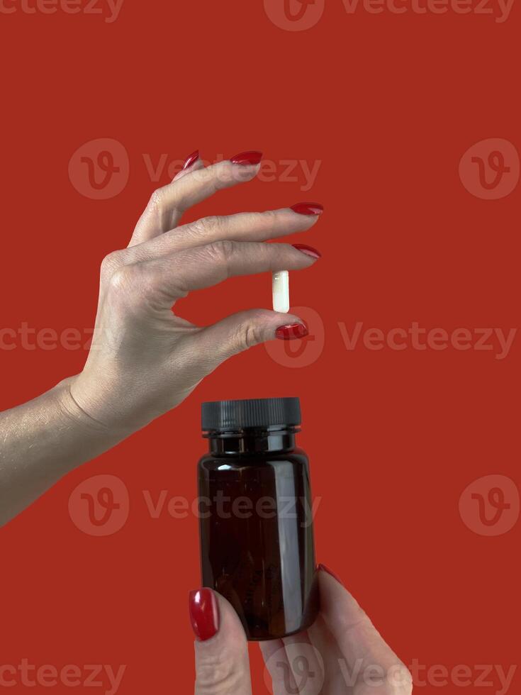 femme en portant pilule et bouteille sur rouge arrière-plan, fermer. espace pour texte photo
