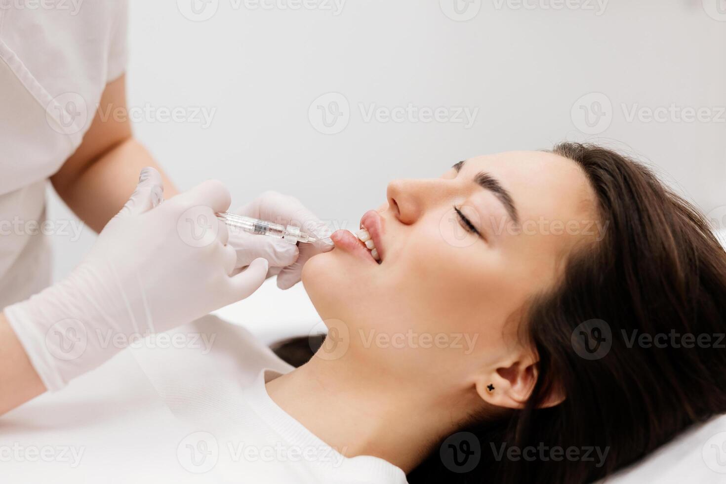 le médecin cosmétologue fait du lèvre augmentation procédure de une magnifique femme dans une beauté salon.cosmétologie peau se soucier. haute qualité photo