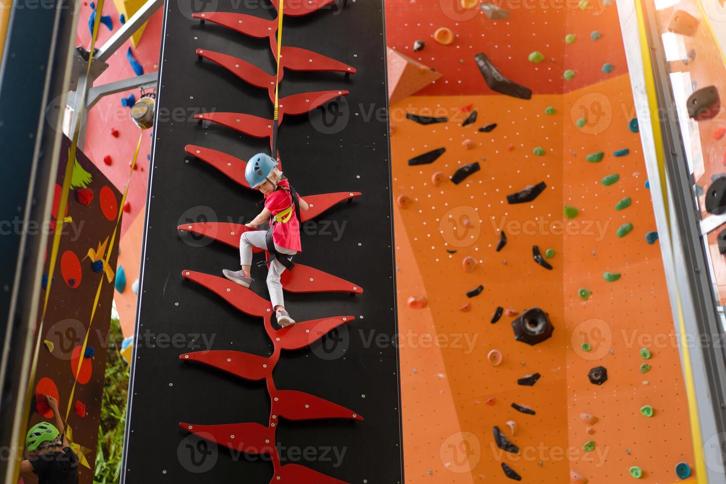 enfant escalade sur mur dans amusement centre. escalade formation pour les enfants. peu fille dans habillé escalade équipement montée haut. extrême actif loisir pour enfants. photo