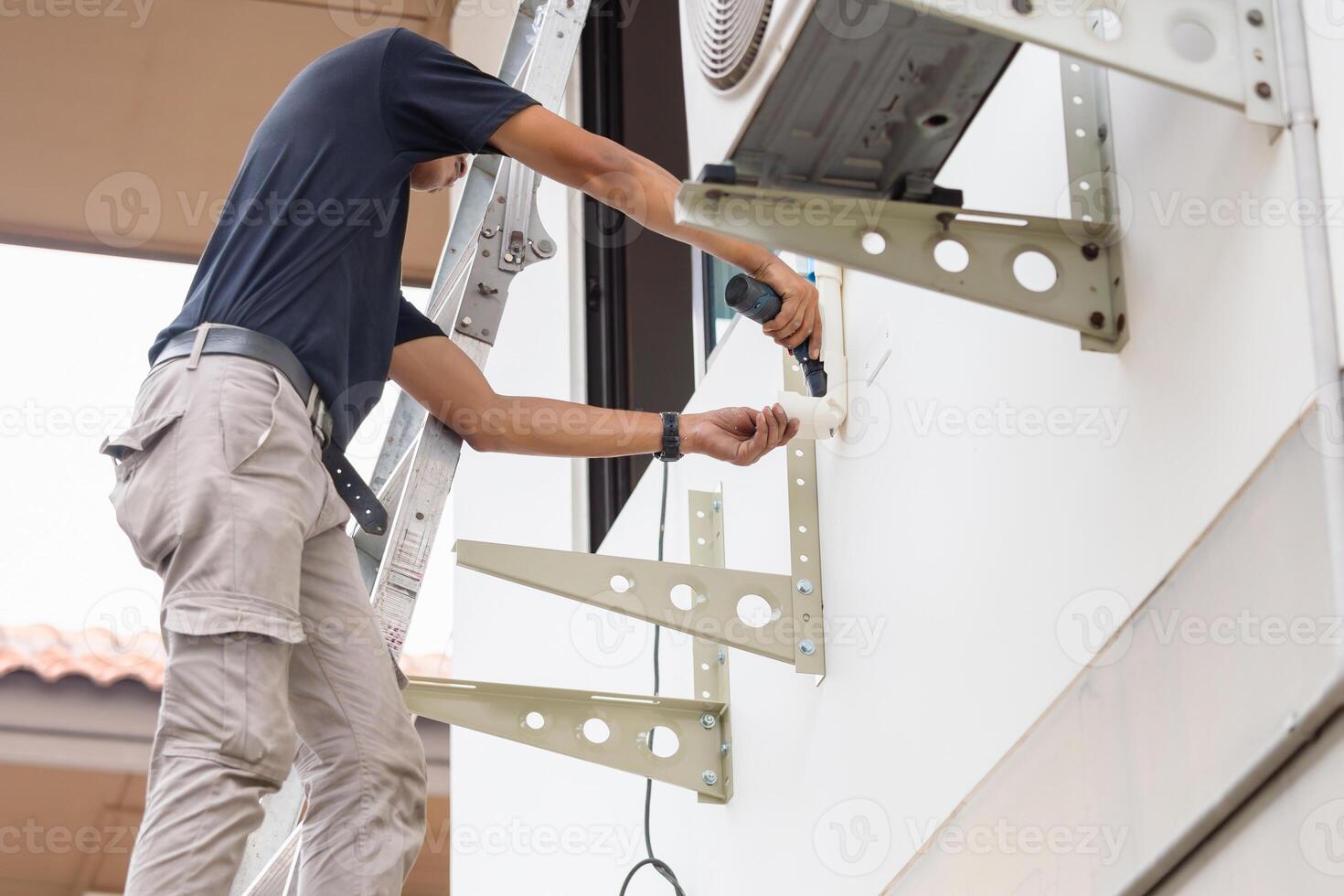 technicien homme en utilisant une Tournevis à réparer et installer Nouveau air Conditionneur, réparer et entretien, entretien, et réparer concepts photo