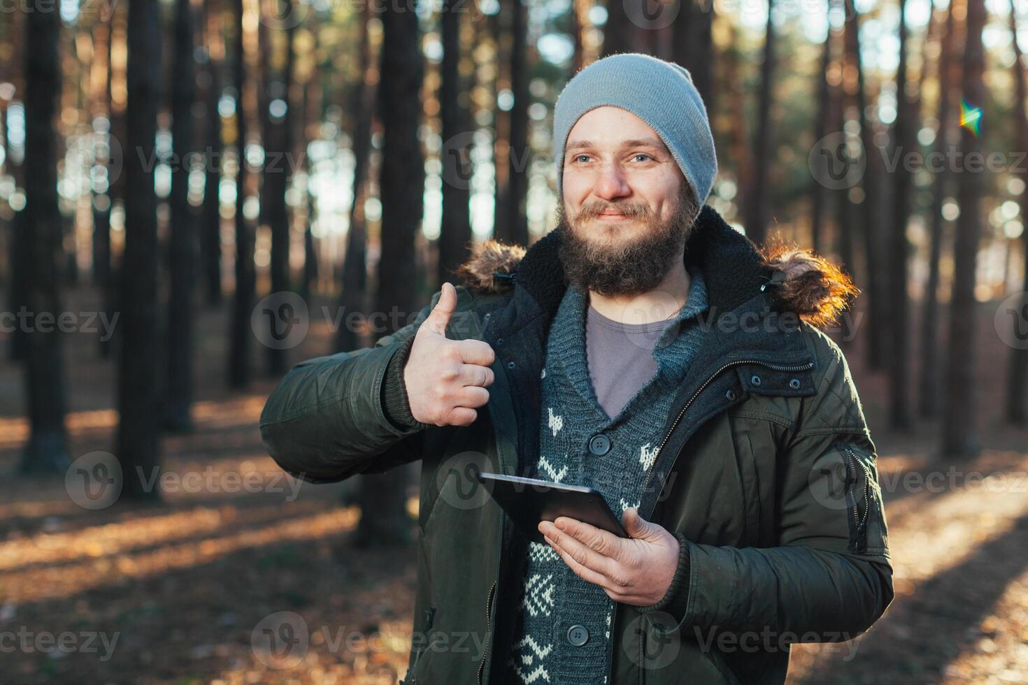 proche en haut portrait de adulte Masculin promeneur en utilisant numérique languette et à la recherche pour emplacement pendant une randonnée dans la nature. homme sur une randonnée en utilisant numérique tablette pour la navigation. photo