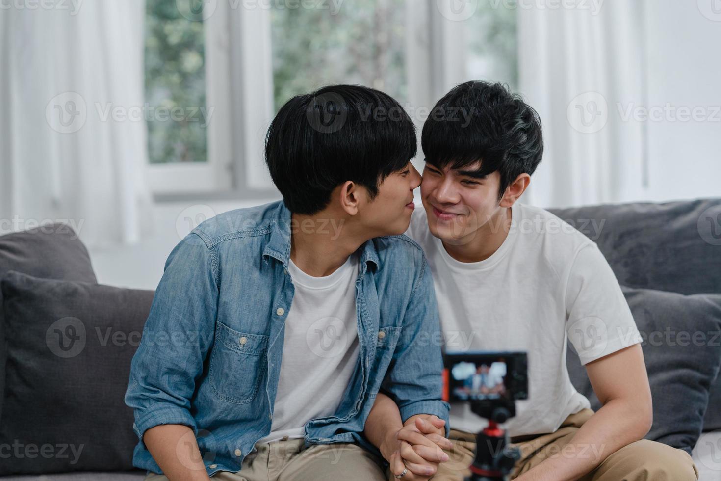 jeune couple gay asiatique couple d'influenceurs vlog à la maison. les adolescents coréens lgbtq heureux se détendent en s'amusant à l'aide de l'enregistrement de la caméra vlog vidéo upload dans les médias sociaux tout en étant allongé sur le canapé dans le salon au concept de maison. photo