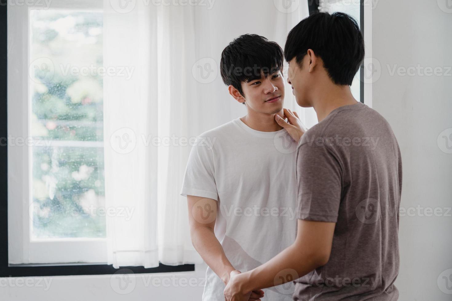 couple gay asiatique debout et s'embrassant près de la fenêtre à la maison. jeunes hommes lgbtq asiatiques s'embrassant heureux se détendre se reposer ensemble passer du temps romantique dans le salon de la maison moderne le matin concept. photo