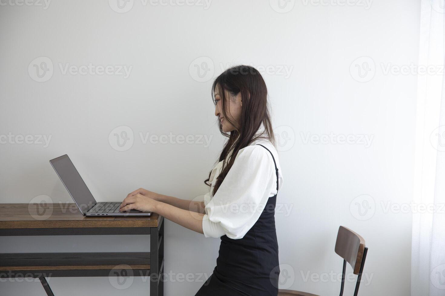 une Japonais femme vérification téléphone intelligent par éloigné travail dans le Accueil Bureau photo