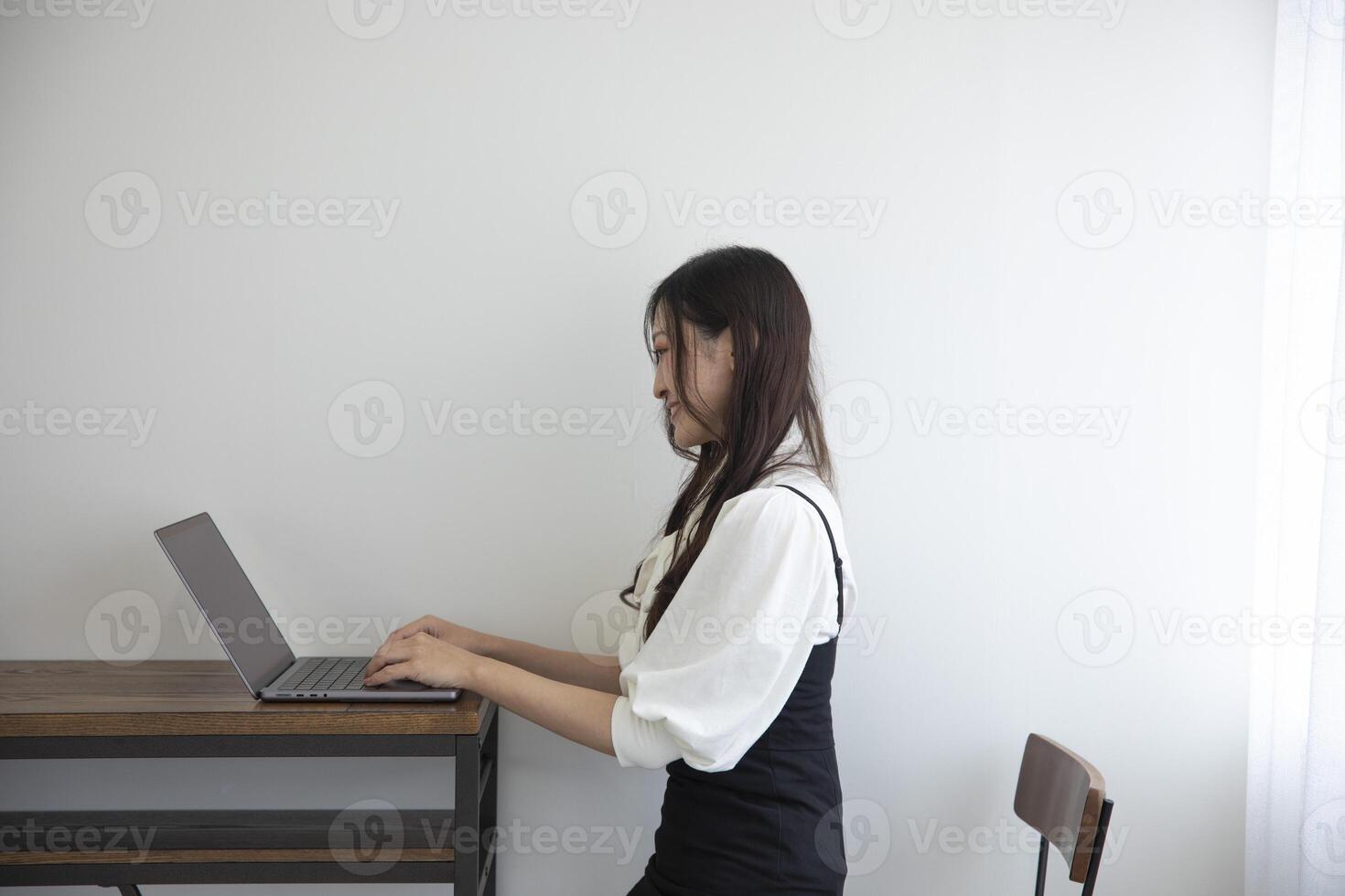 une Japonais femme vérification téléphone intelligent par éloigné travail dans le Accueil Bureau photo