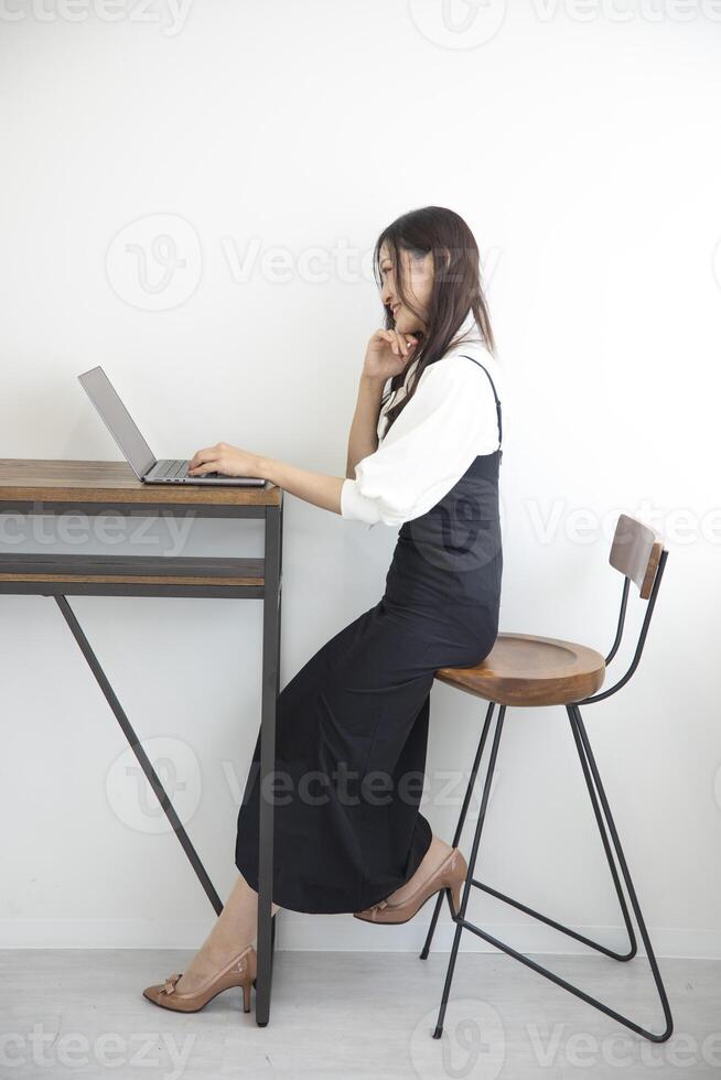 une Japonais femme vérification téléphone intelligent par éloigné travail dans le Accueil Bureau photo