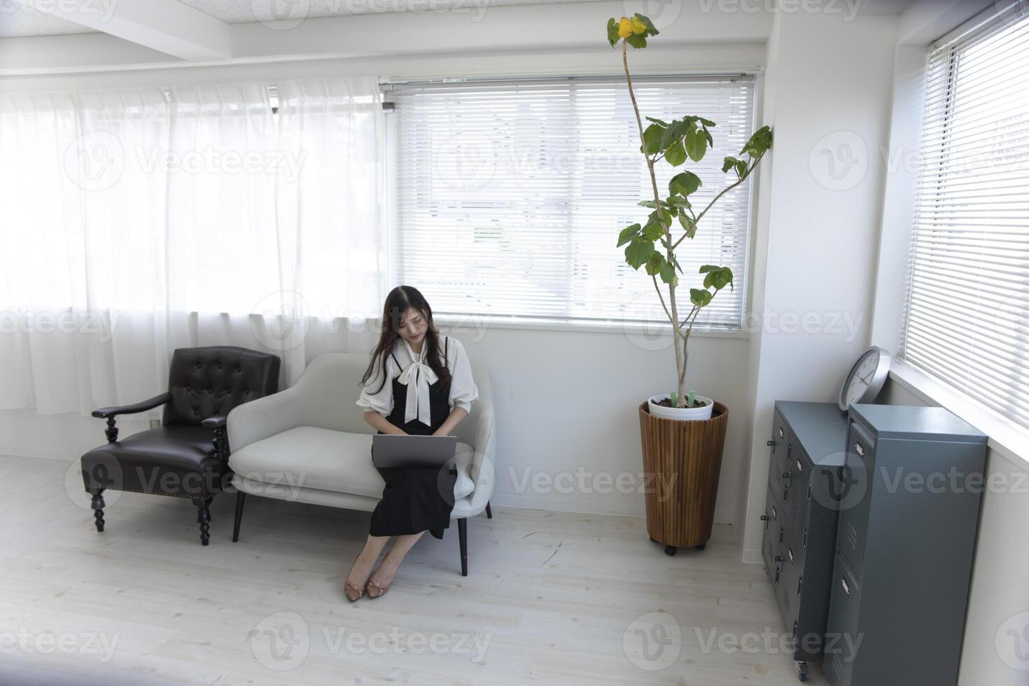 une Japonais femme vérification téléphone intelligent par éloigné travail dans le Accueil Bureau photo