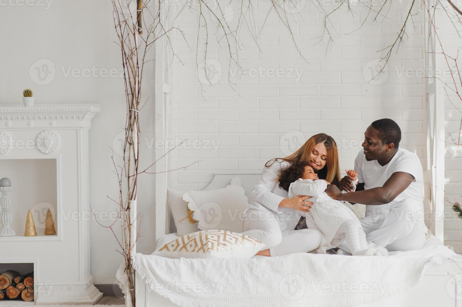 portrait de content multiracial Jeune famille mensonge sur confortable blanc lit à maison, souriant international maman et papa relaxant avec peu biracial fille enfant posant pour image dans chambre photo