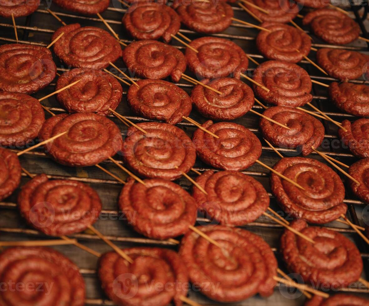 frit spirale saucisses sur un électrique barbecue un barbecue gril. électrique plaque à cuisinier aliments. allemand bratwurst porc saucisse. photo